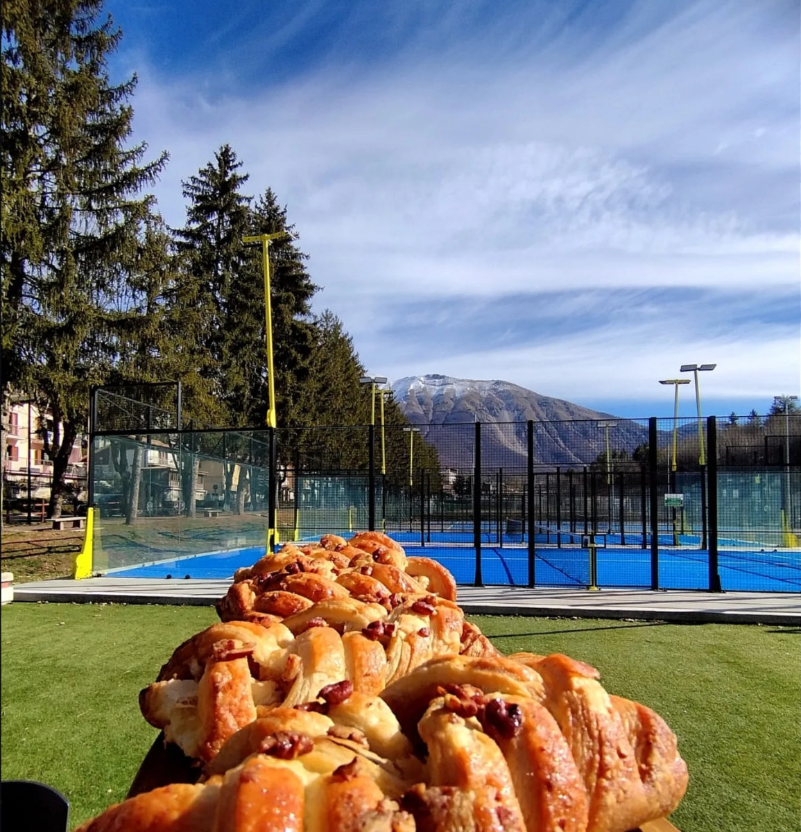 Colazione con treccia dolce davanti ai campi da padel e alla montagna